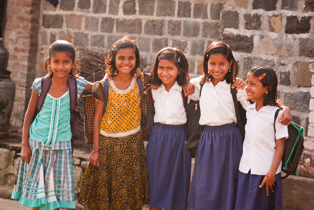 A group of girls standing together in a public place, smiling and enjoying their time.