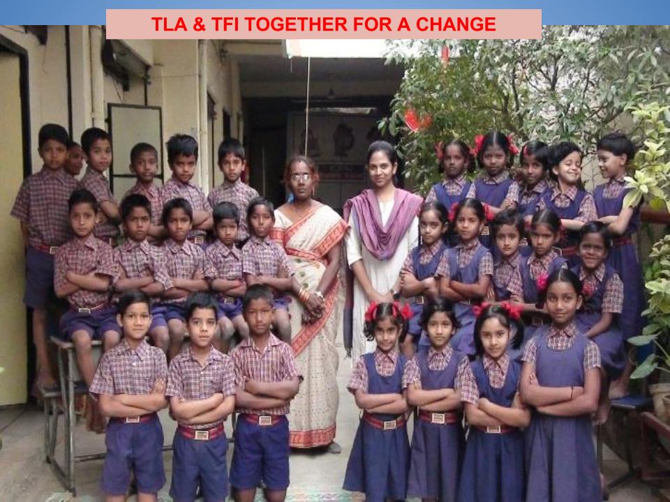 A group of children posing for a photo with their teachers, smiling together in a friendly and cheerful setting.
