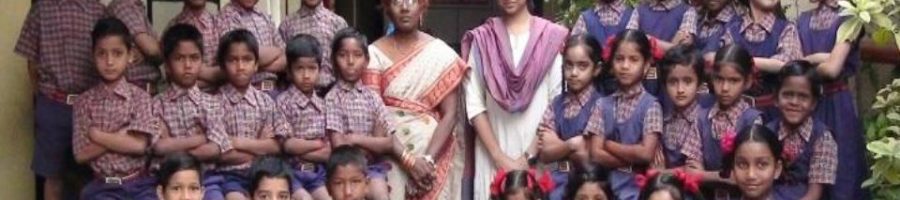 A group of children posing for a photo with their teachers, smiling together in a friendly and cheerful setting.